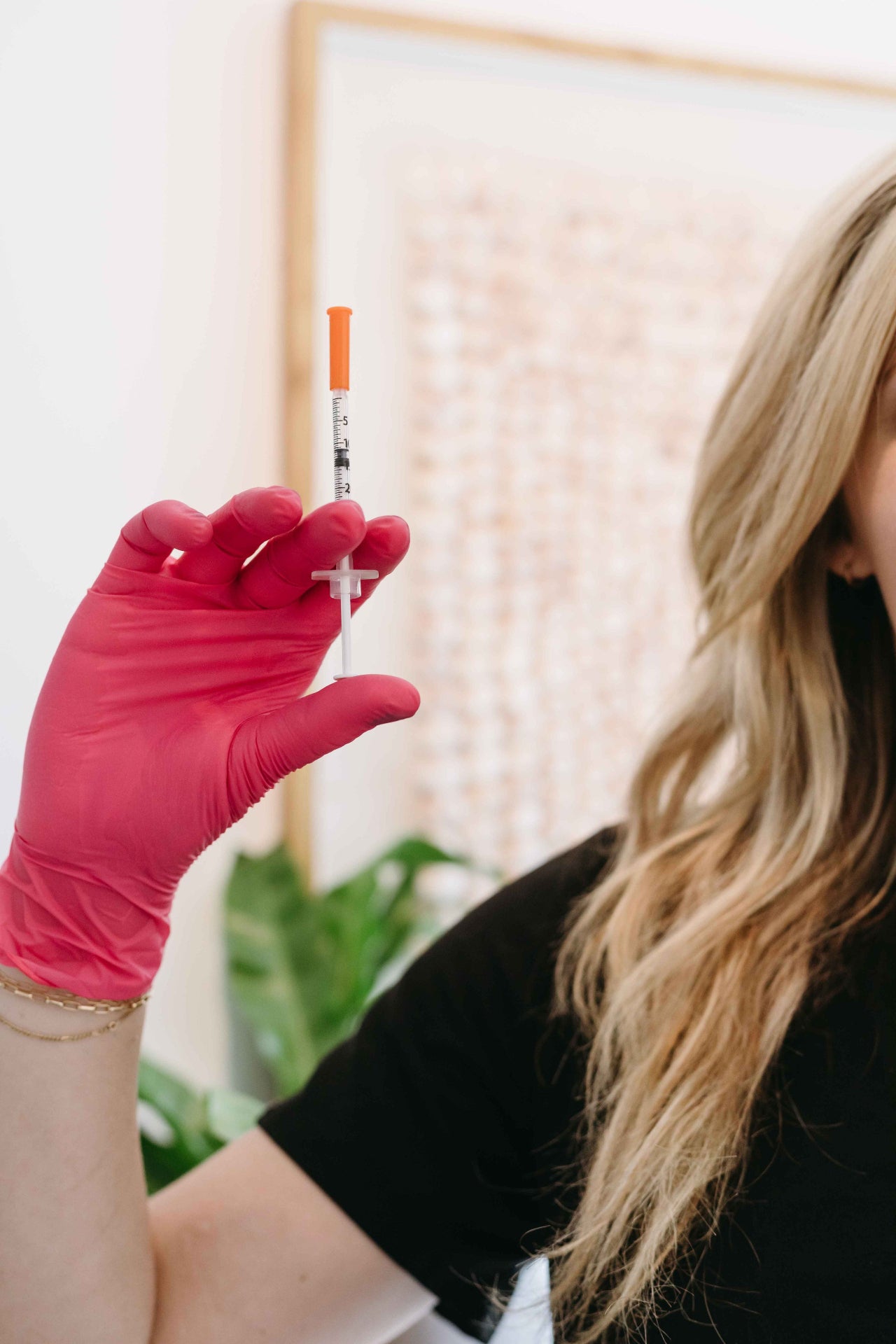 Person wearing a pink glove holding a syringe with a blurred background