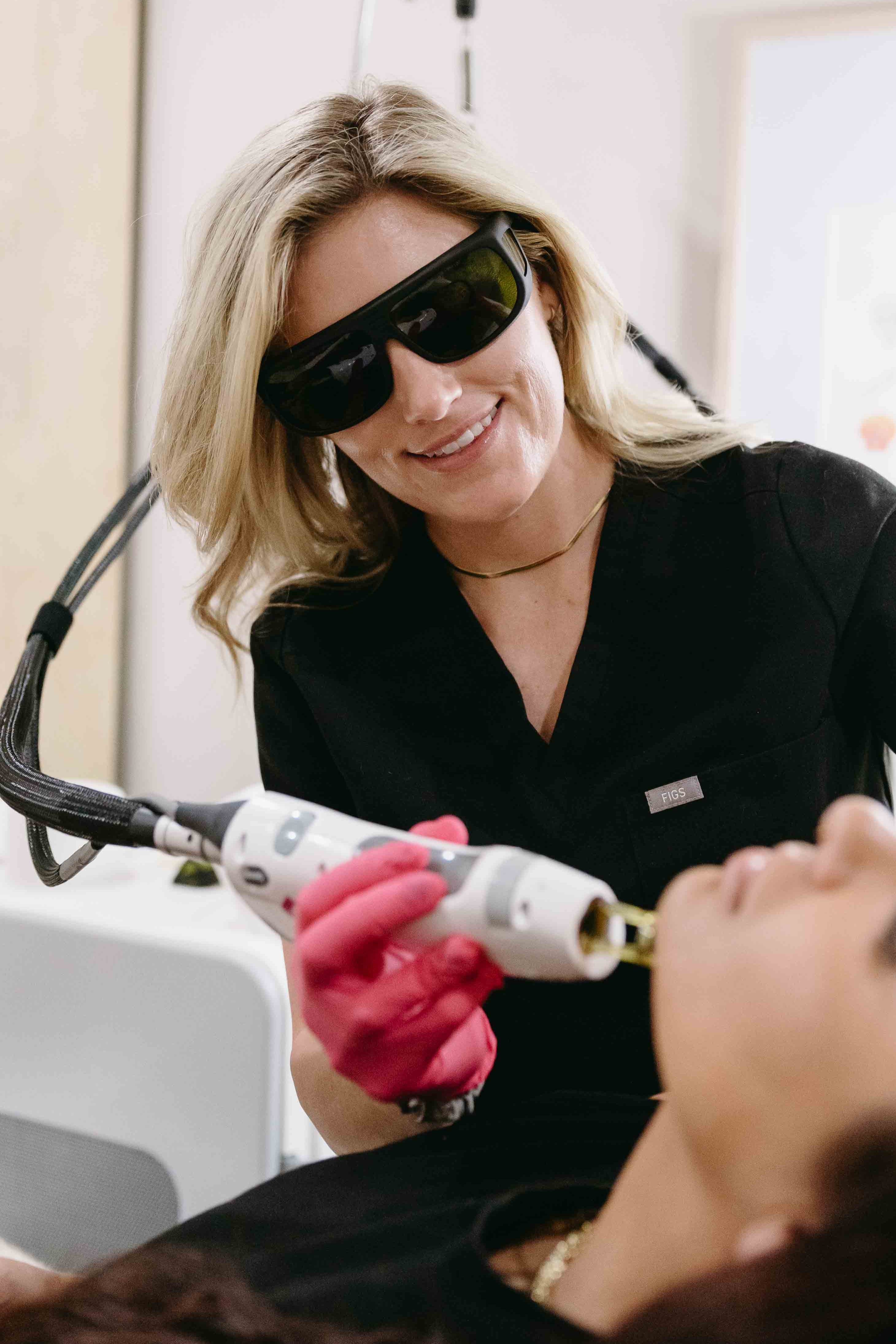 Person receiving a laser treatment from a professional wearing protective eyewear.