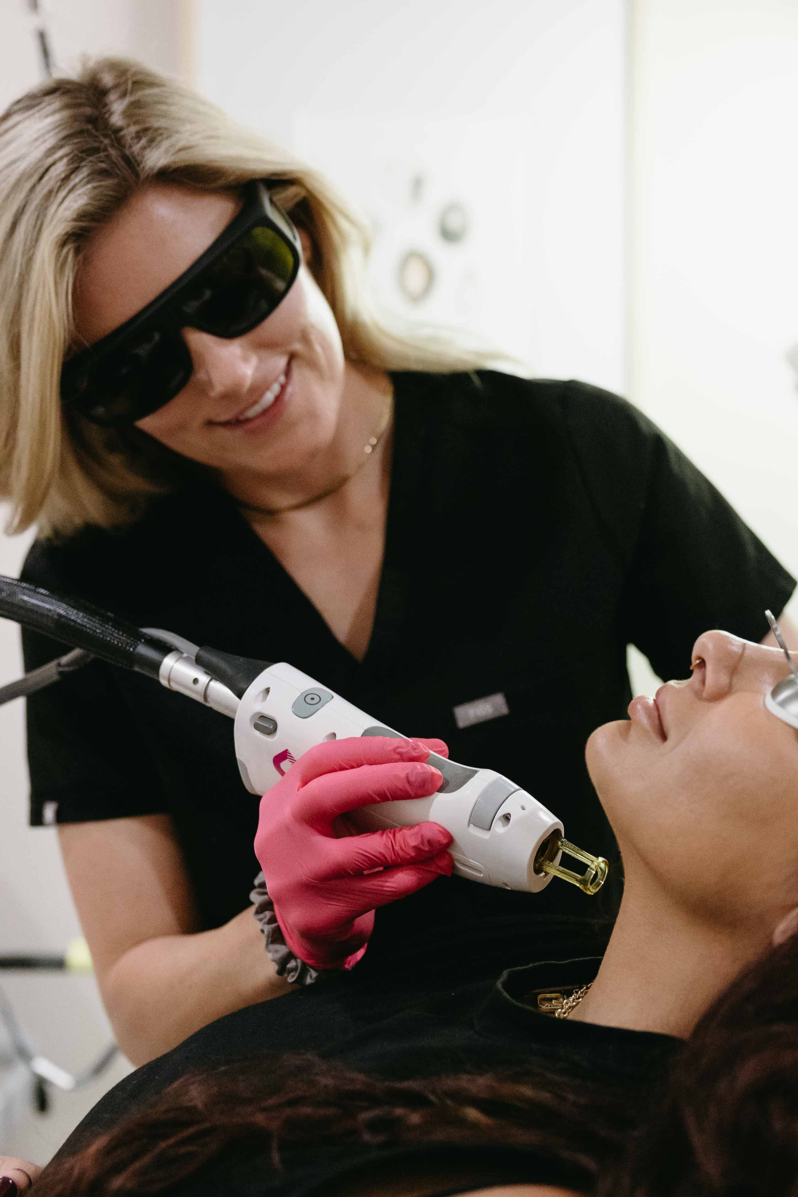 Woman receiving laser treatment from a professional in a clinical setting.